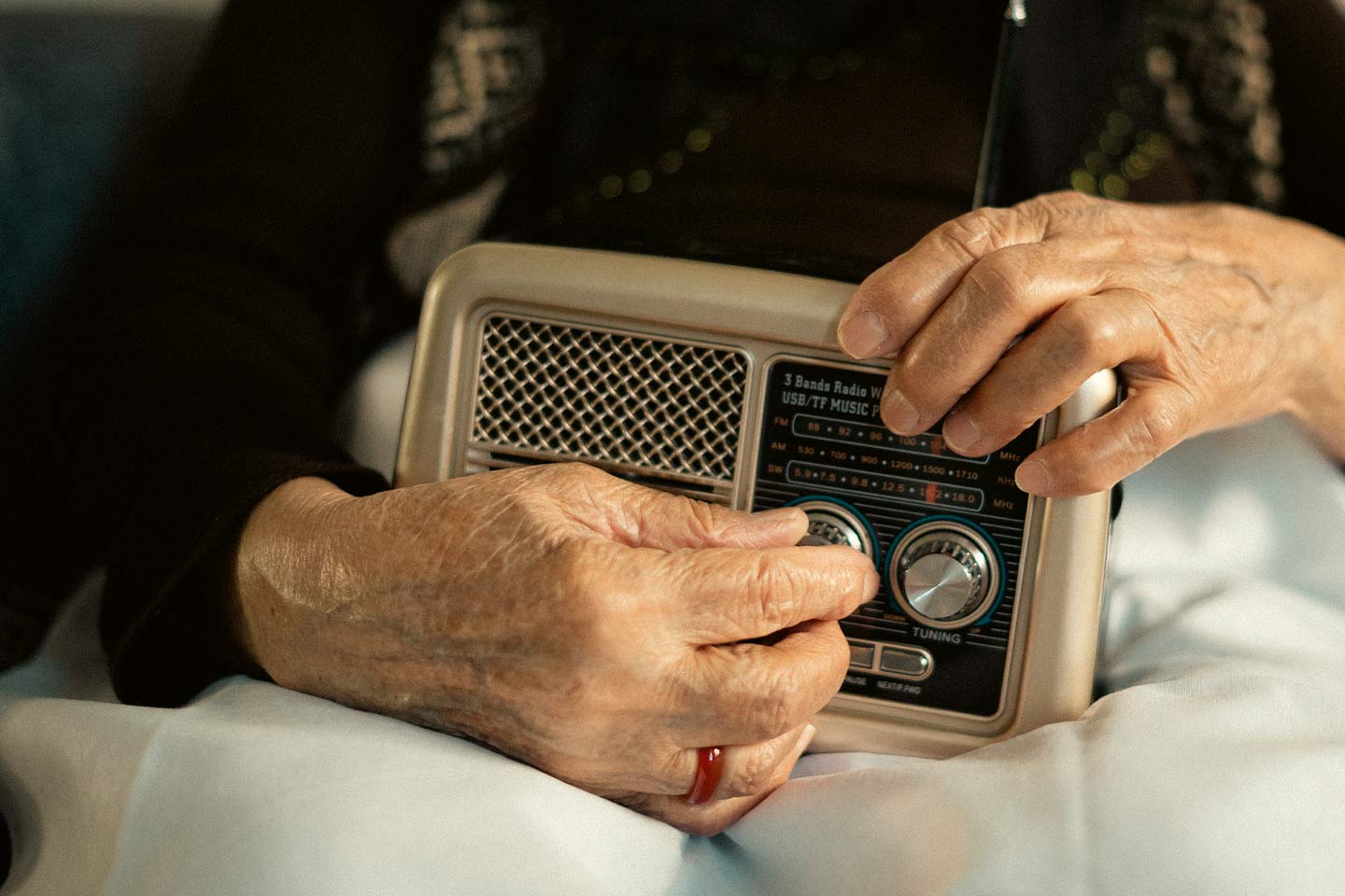 Photo of hands turning the knobs of a traditional radio