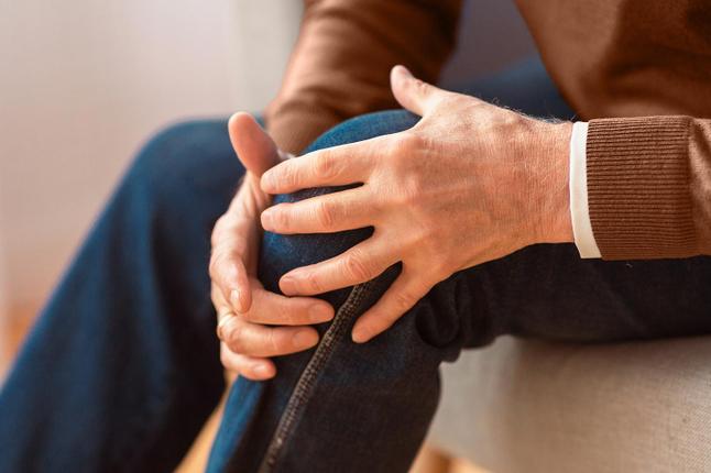 Photo of hands clutching a knee in closeup