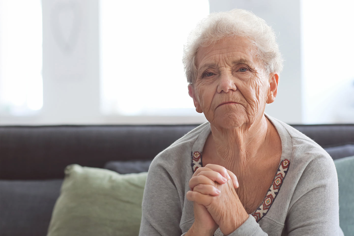 Photo of a woman in a grey top with hands clasped