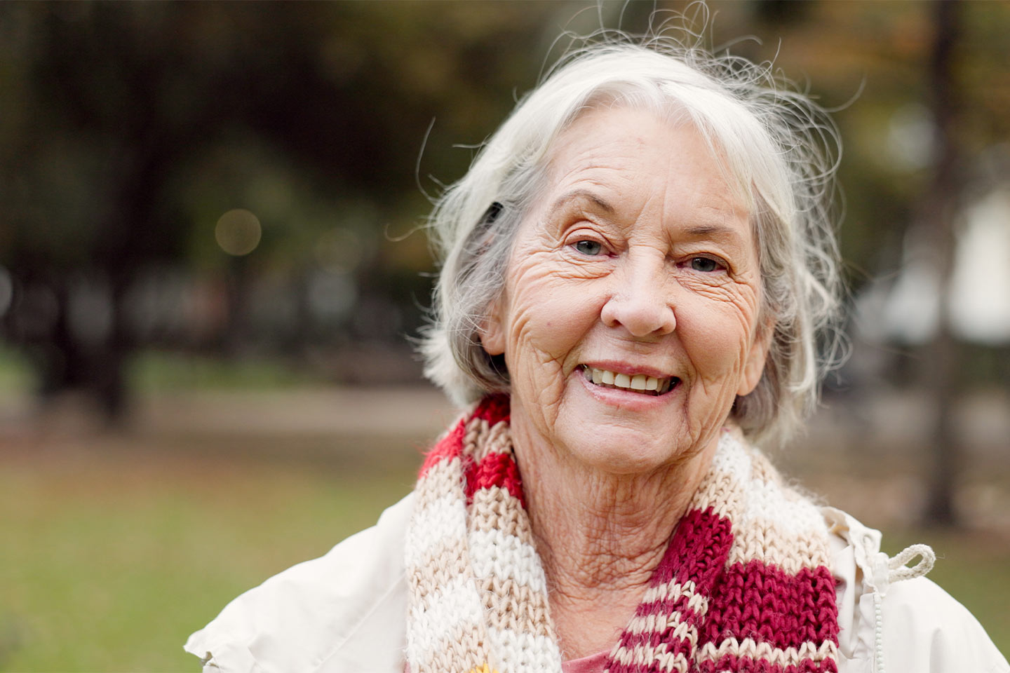 Photo of a woman in a hand knitted scarf smiling at us