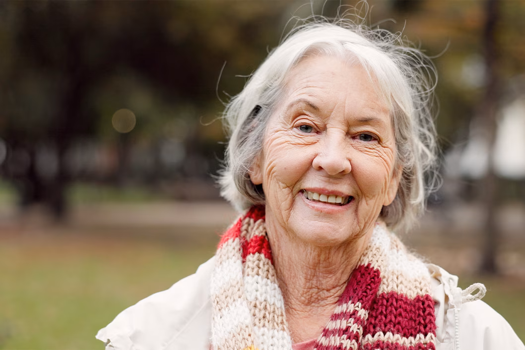 Photo of a woman in a hand knitted scarf smiling at us