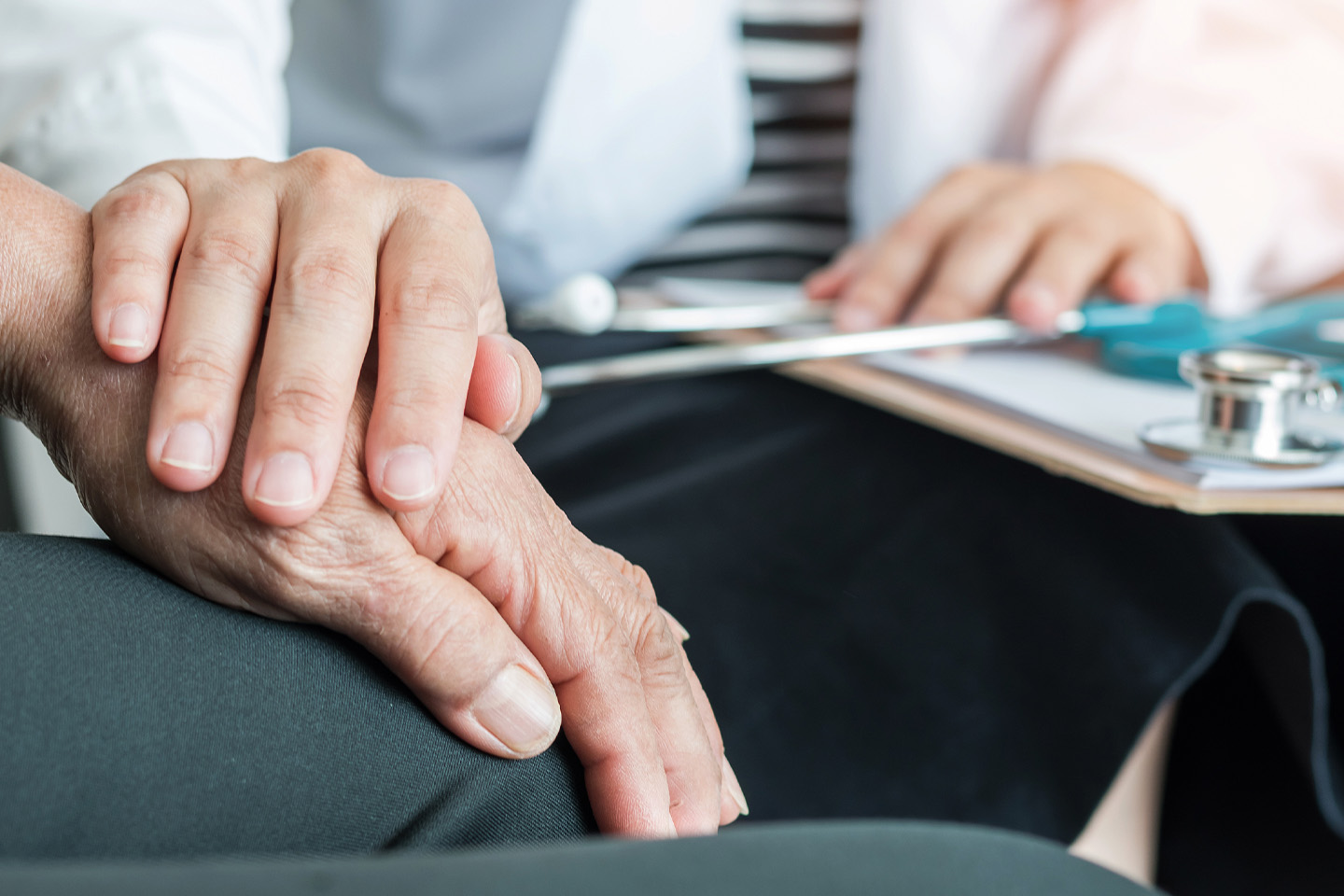 Image of a doctor's hand's resting on an elderly man's hands