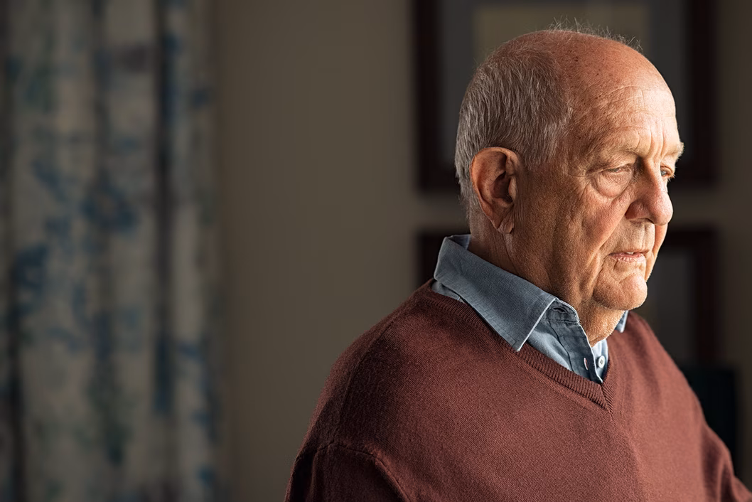 Photo of a man in a brown jumper and chambray shirt