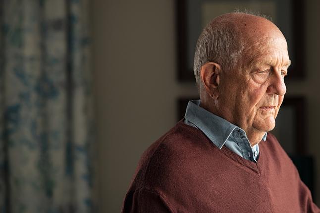 Photo of a man in a brown jumper and chambray shirt