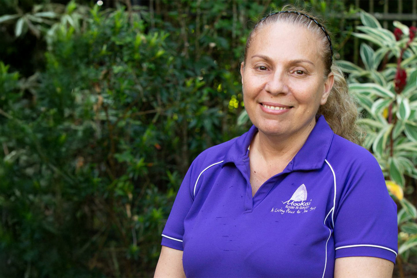Photo of a smiling woman wearing a purple polo shirt