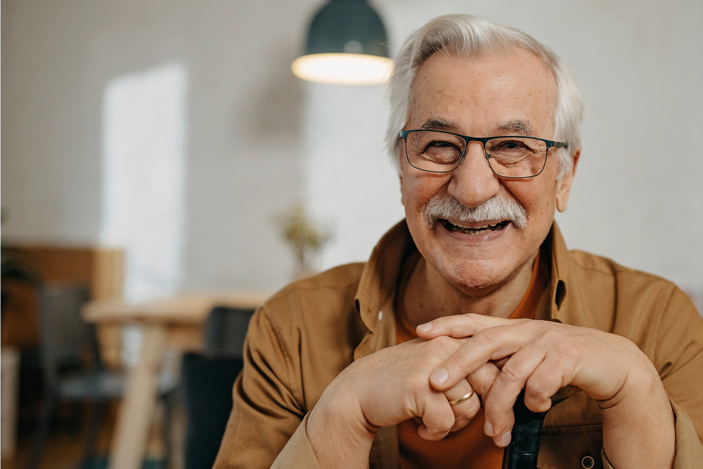 Photo of a man laughing in a brown shirt