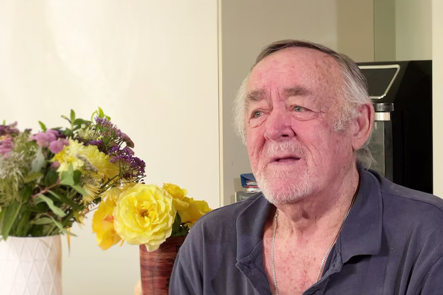 Photo of sad man with flower bouquets behind him