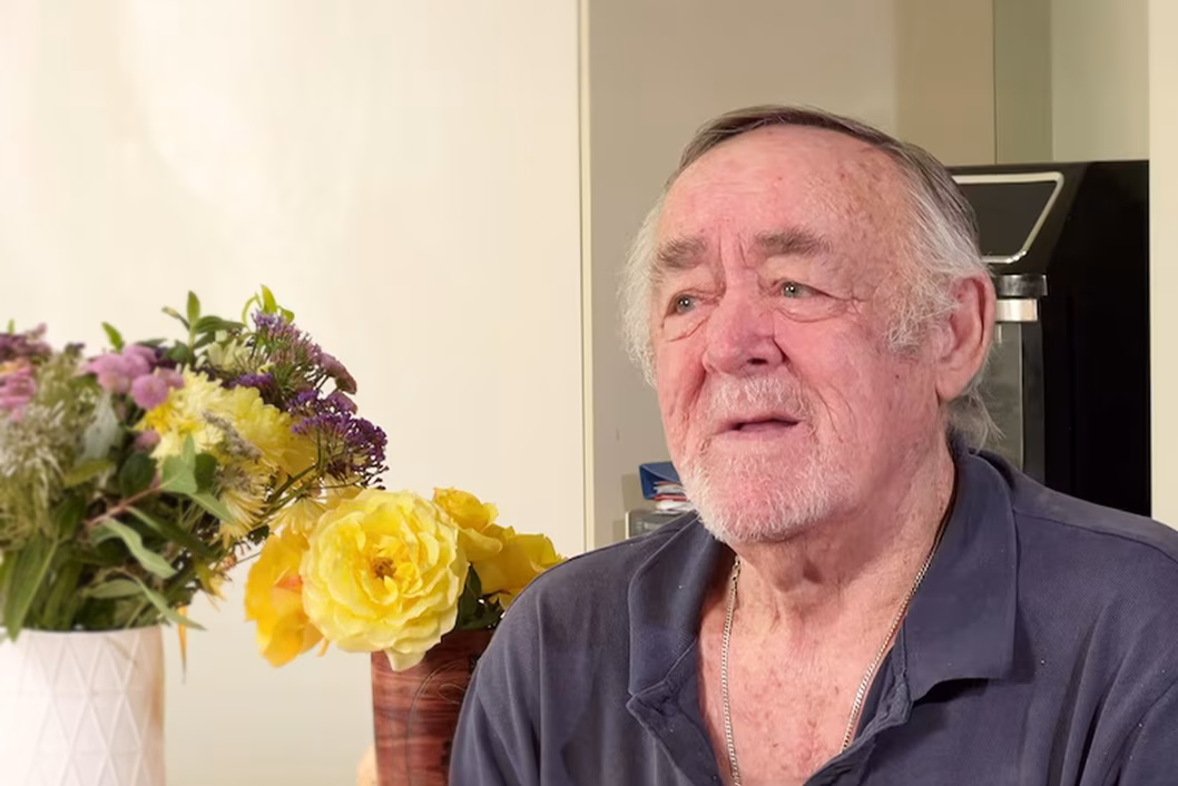 Photo of sad man with flower bouquets behind him