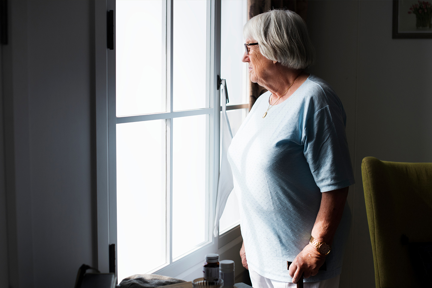 Photo of a woman in pale blue looking out of her window
