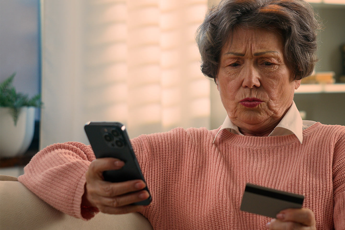 Photo of a concerned woman looking at her phone and credit card