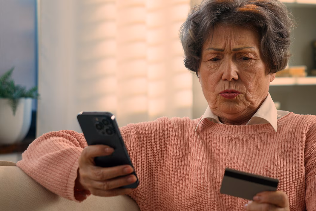 Photo of a concerned woman looking at her phone and credit card