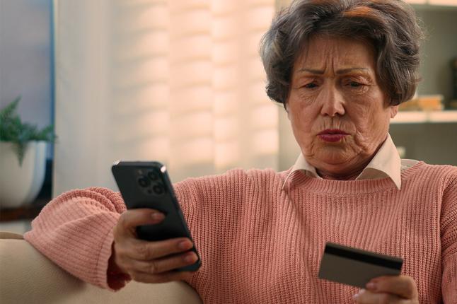 Photo of a concerned woman looking at her phone and credit card