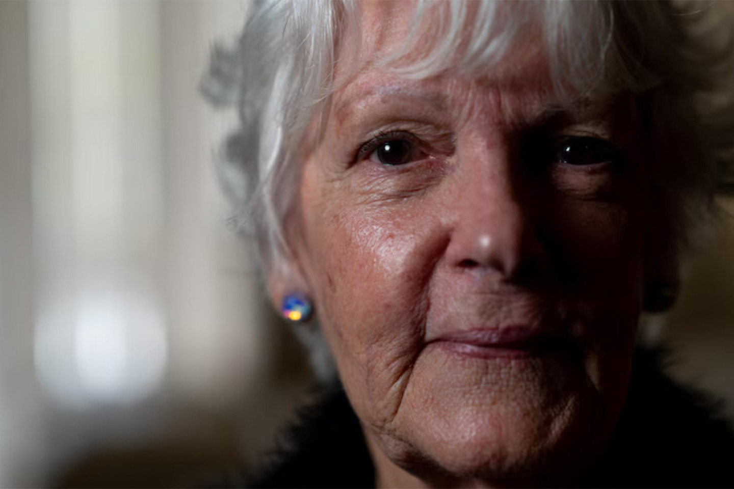 Photo of a woman with sparkly earrings in a poorly lit room