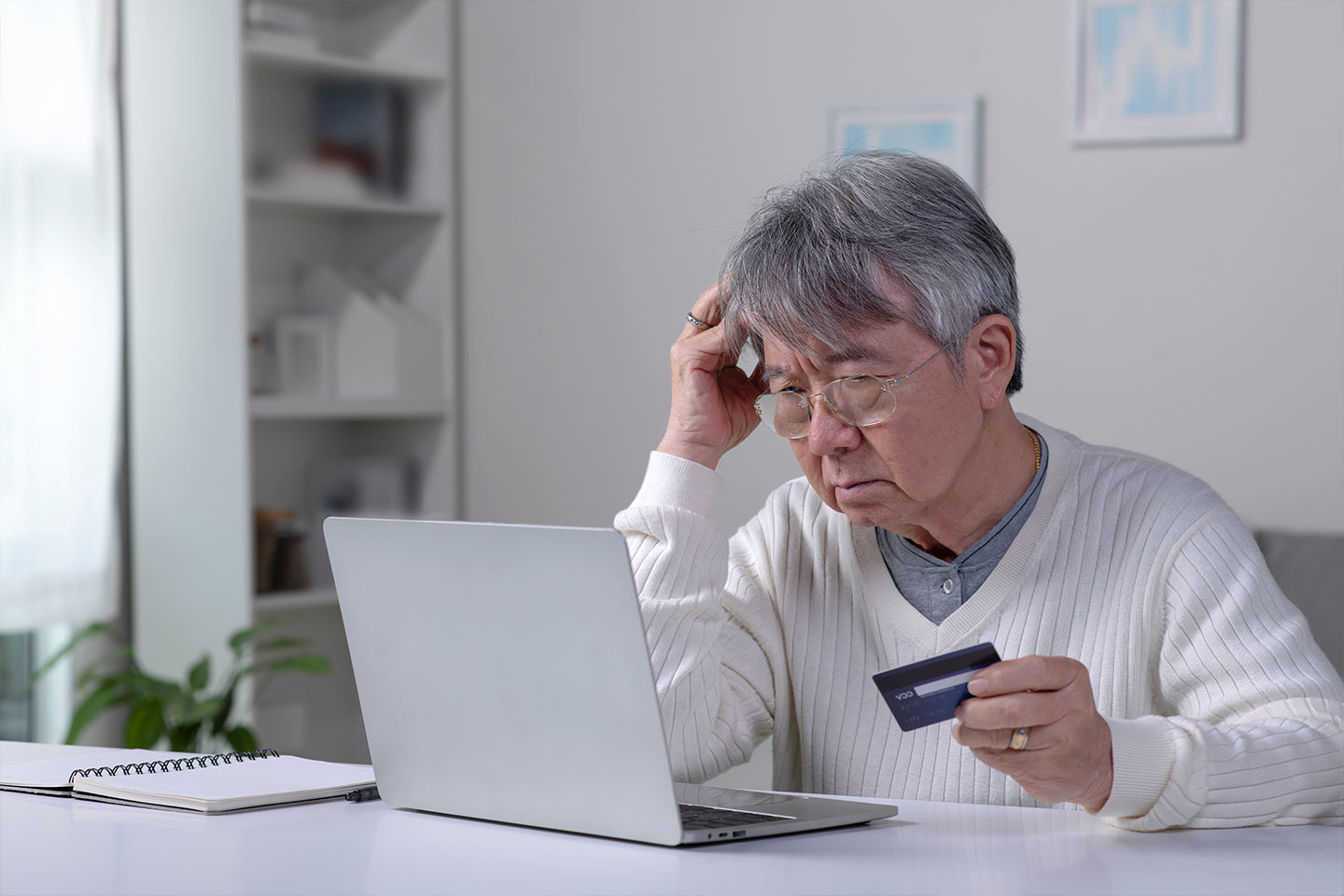Photo of man holding credit card staring at computer