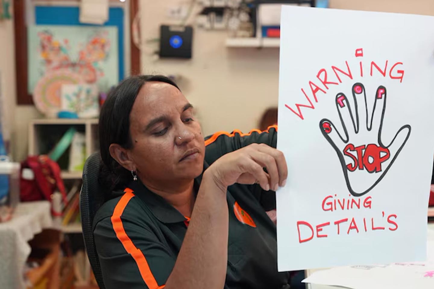 Photo of a woman holding up a poster warning against scams