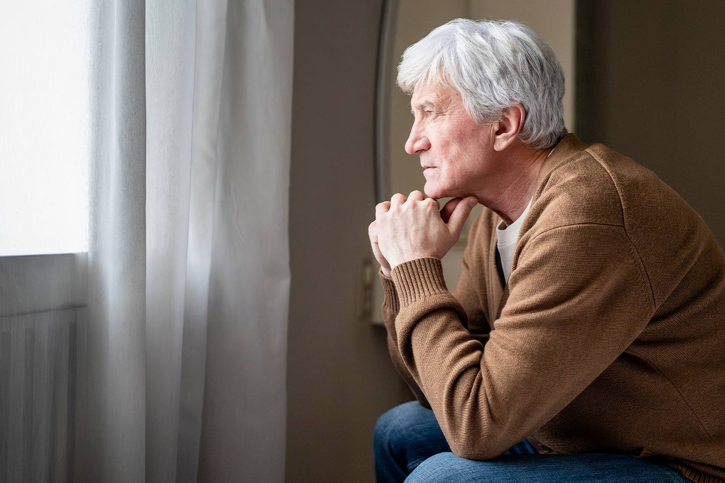 Photo of a man looking out a window with his chin on his hands
