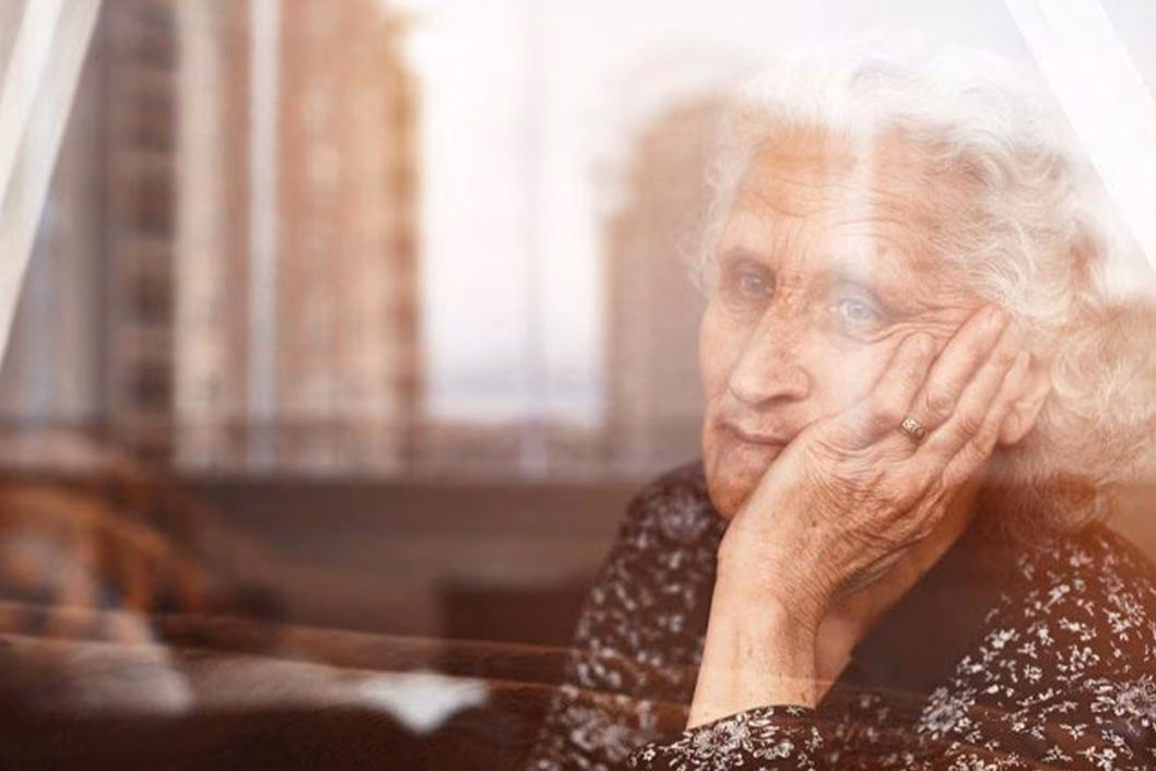 Photo of older lady looking pensively through a window