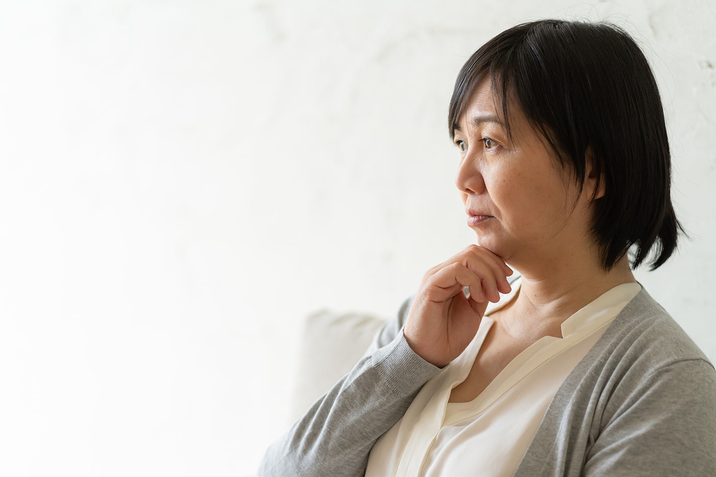 Photo of a woman in a grey cardigan with her hand on her chin