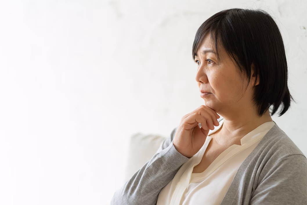 Photo of a woman in a grey cardigan with her hand on her chin