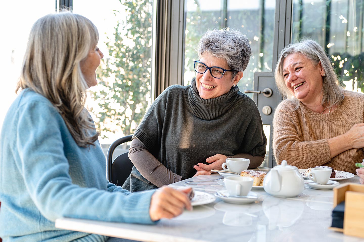 Photo of three women enjoying a laugh over tea and cake