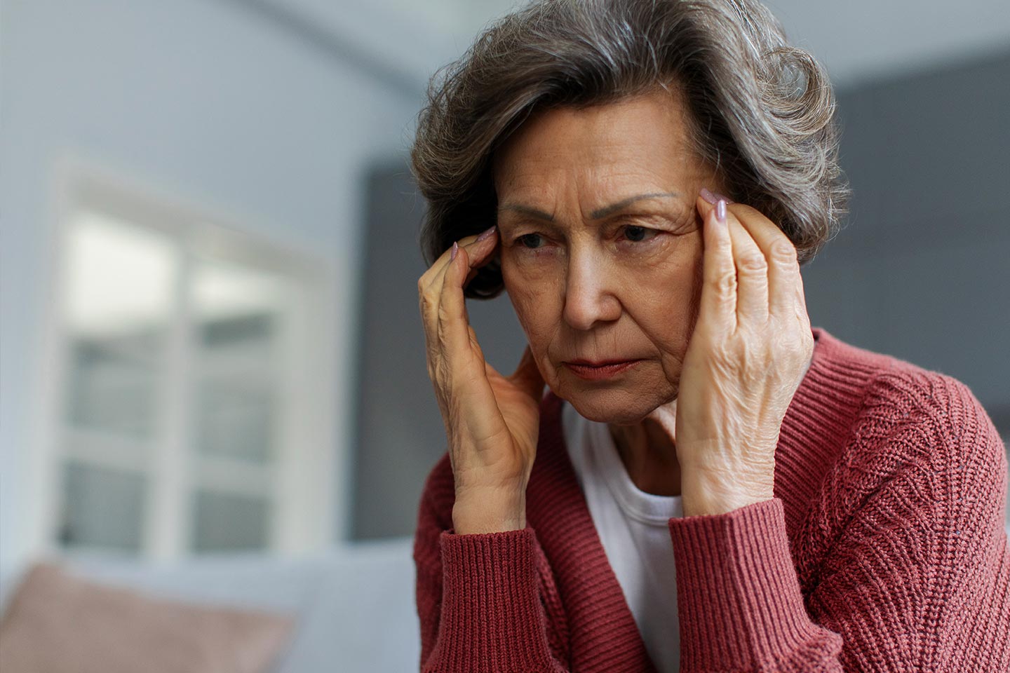 Photo of woman in a red cardigan rubbing her temples