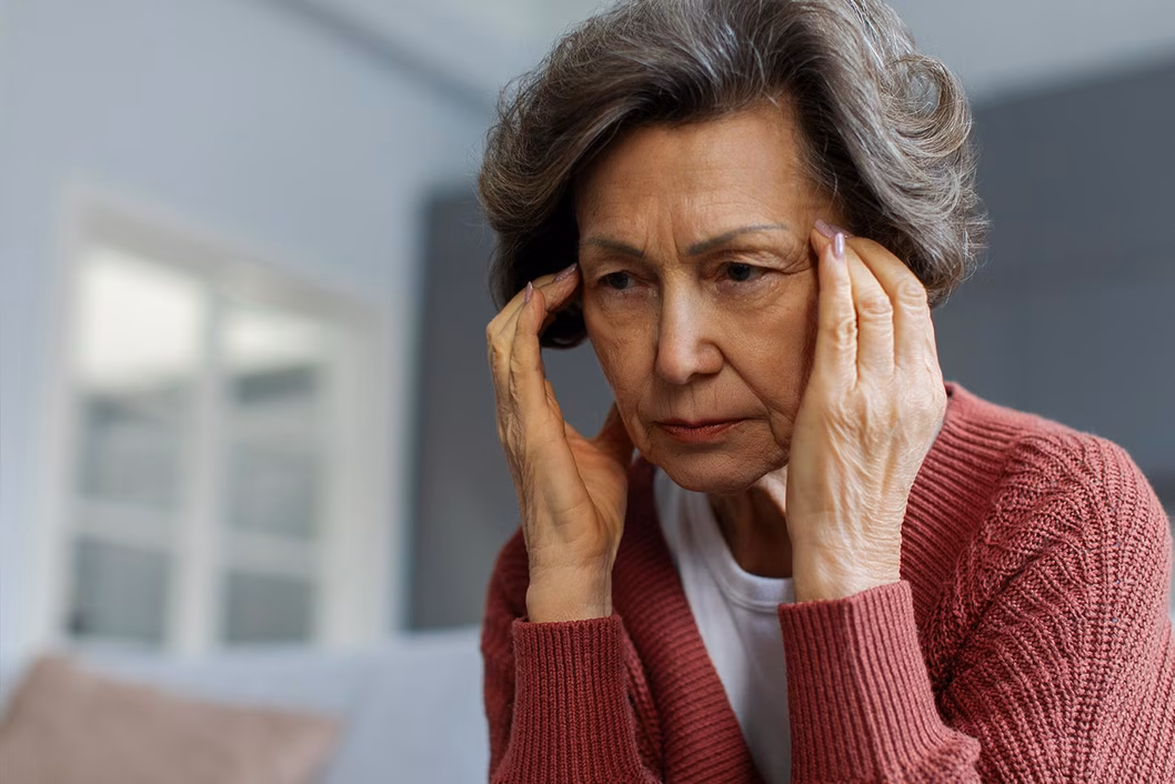 Photo of woman in a red cardigan rubbing her temples