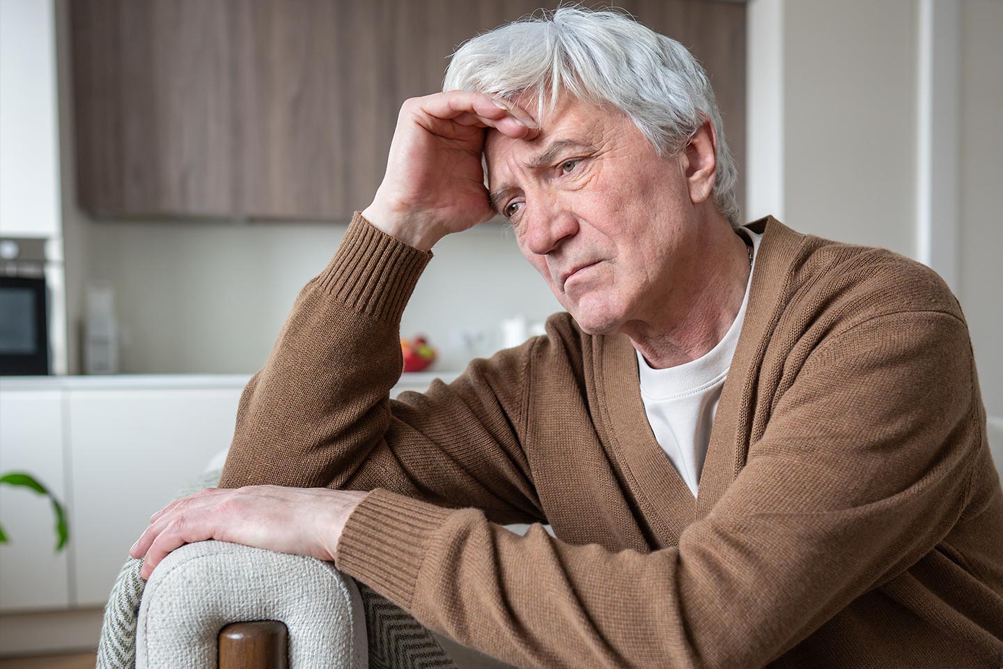 Photo of a despondent man resting his head on his hand