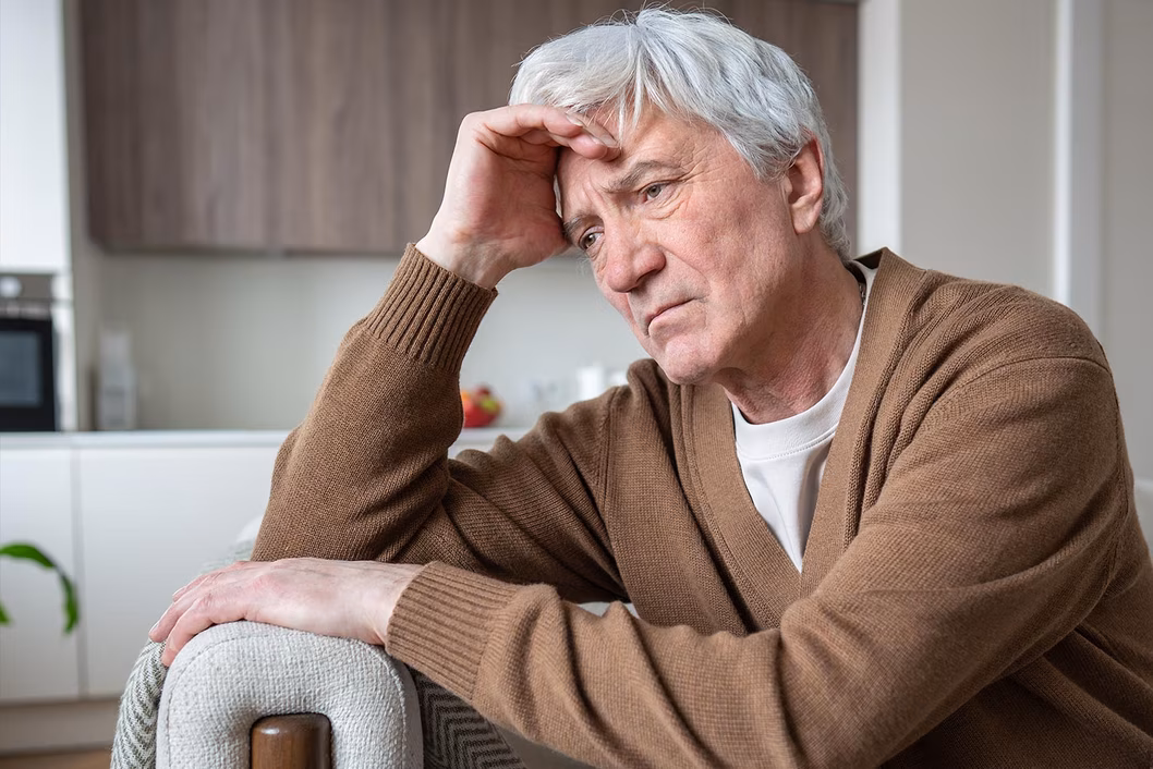 Photo of a despondent man resting his head on his hand