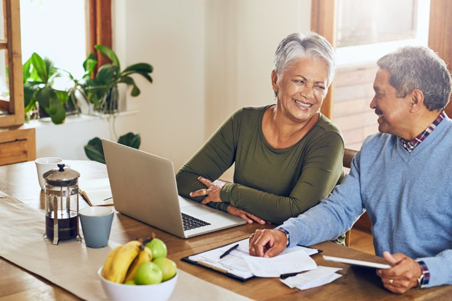 Photo of a couple smiling as they work on a laptop
