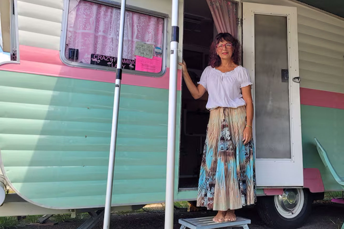 Photo of a woman standing in front of a retro caravan