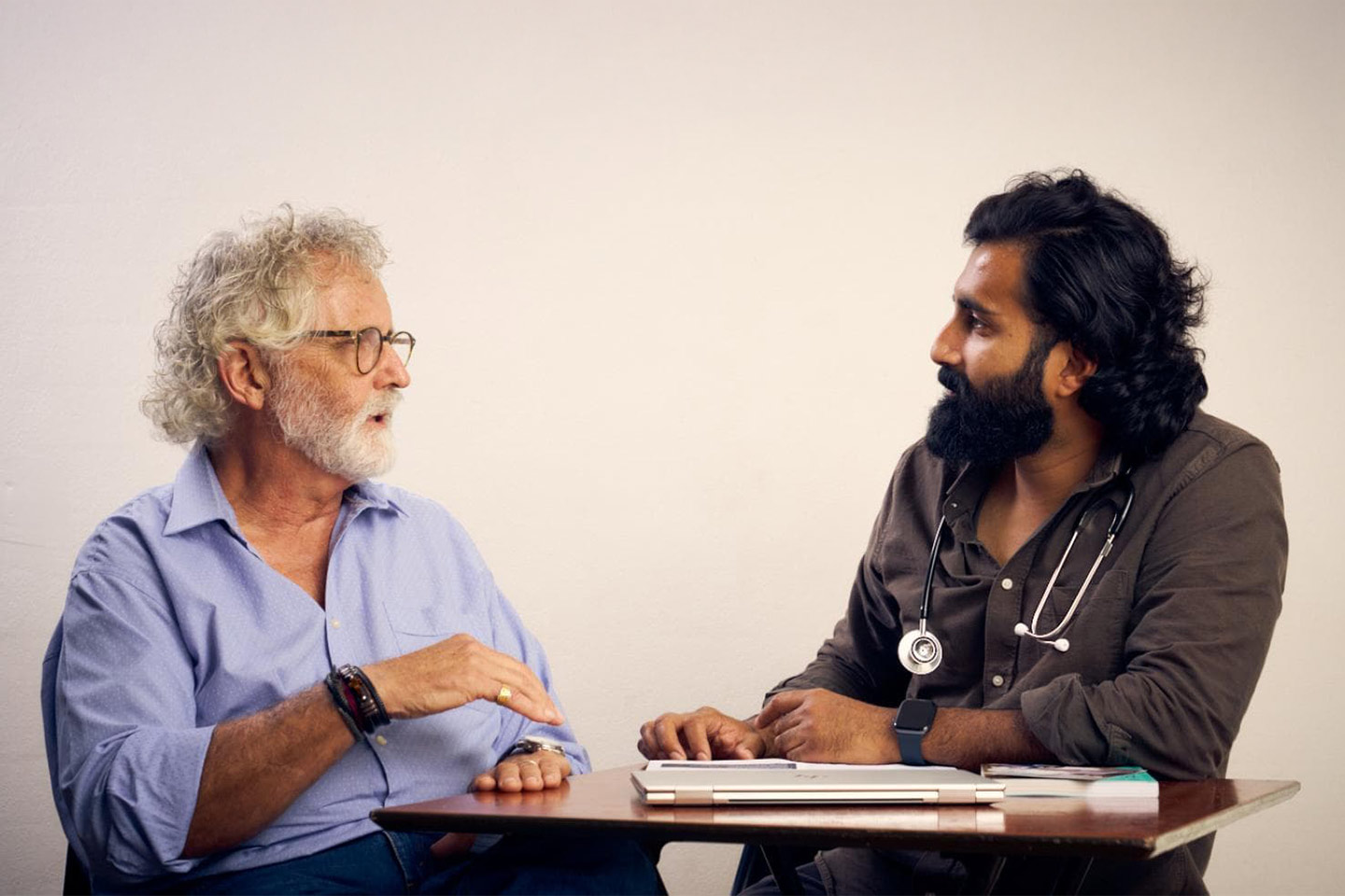 an older man and a doctor talking across a desk