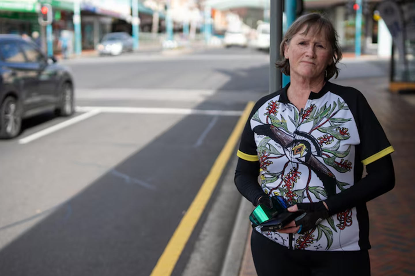 Photo of a woman in cycling gear standing by a city street