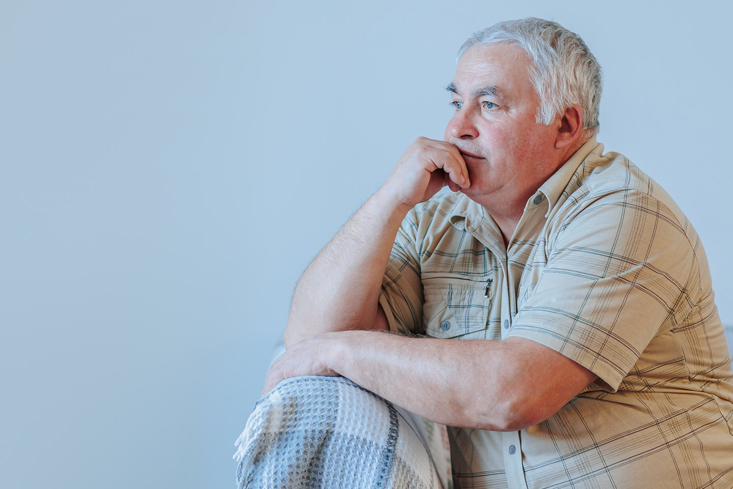 Photo of a man in a cream plaid shirt sitting on a sofa