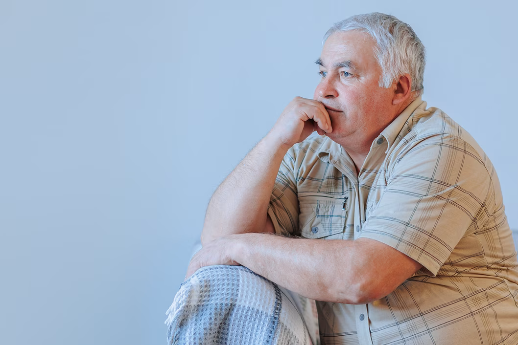 Photo of a man in a cream plaid shirt sitting on a sofa