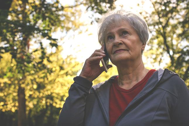 Image of an older woman who is outside and holding a smartphone to her ear.