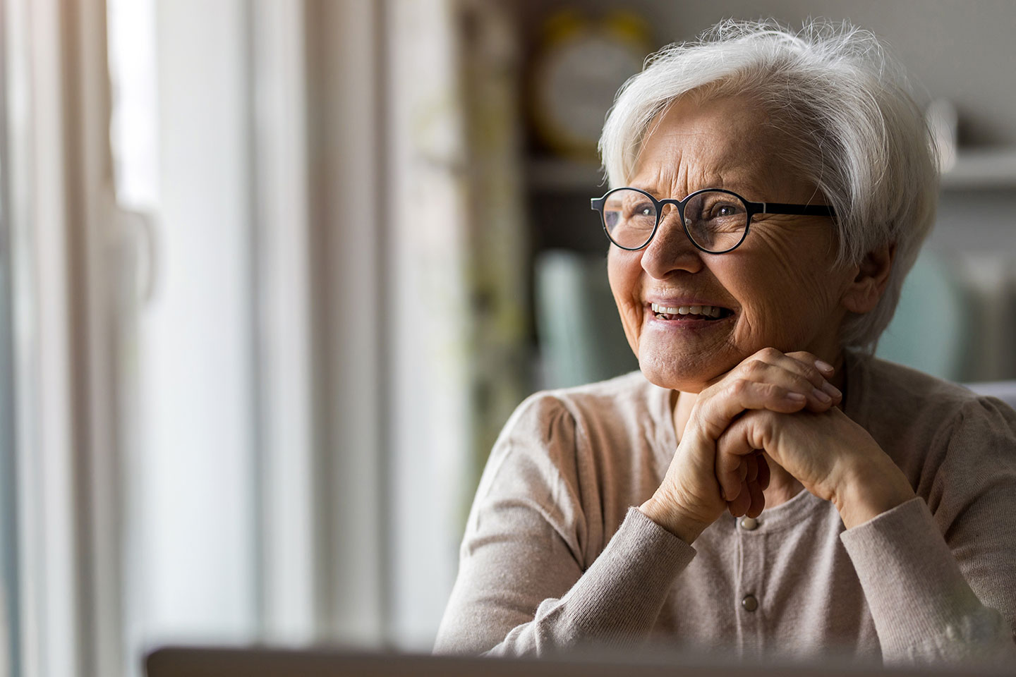 Photo of a woman smiling with her hands clasped
