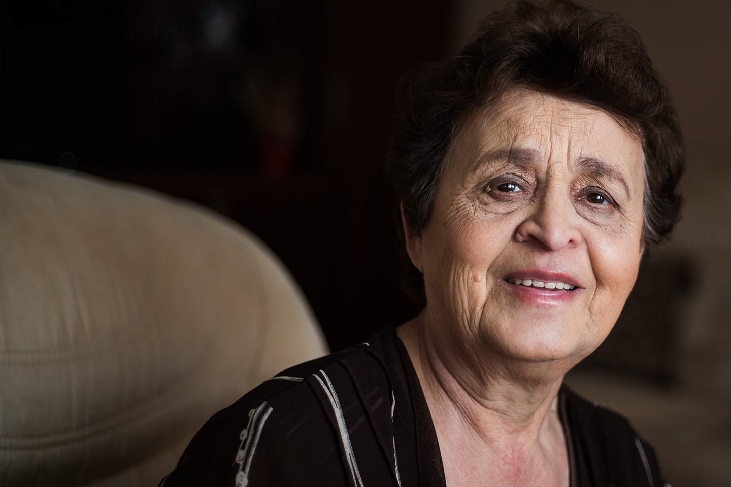 Photo of woman smiling on a taupe sofa