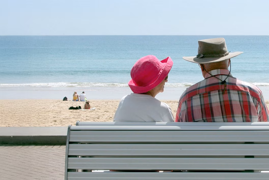 Photo of a couple sitting on a bench at the seaside