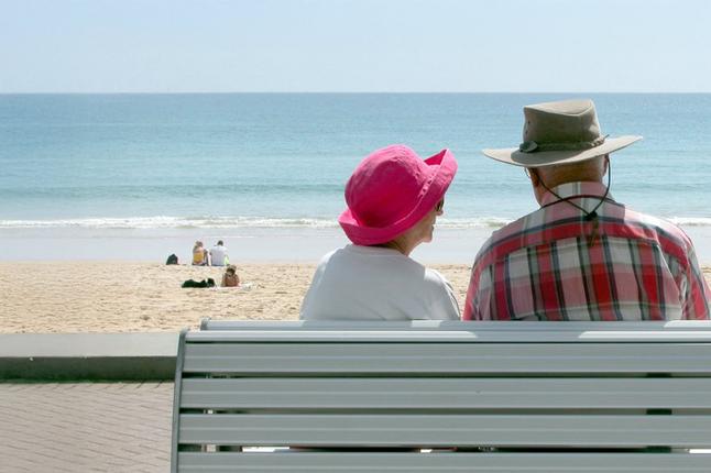 Photo of a couple sitting on a bench at the seaside