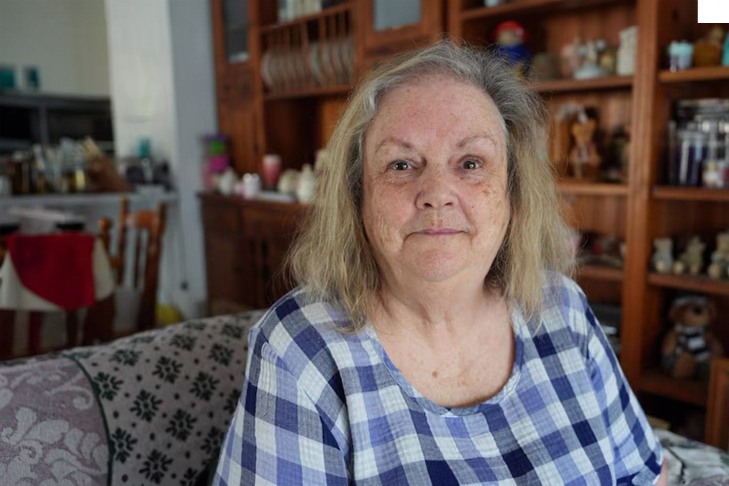 Photo of a woman wearing a blue checked dress in a room full of knick knacks