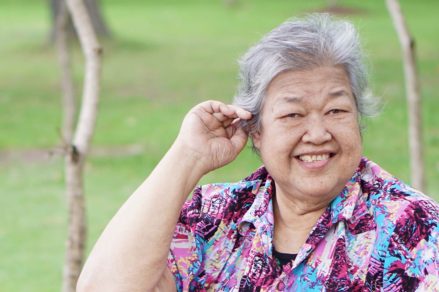 Photo of a woman in a blue and purple shirt smiling outdoors