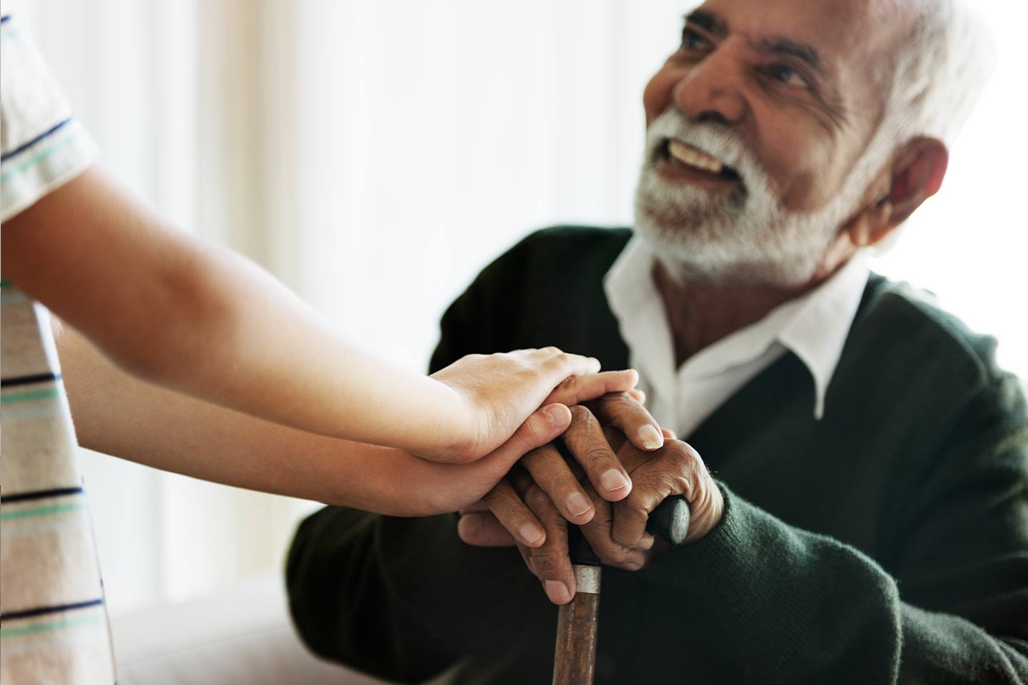 Photo of a man with his hands on a walking stick