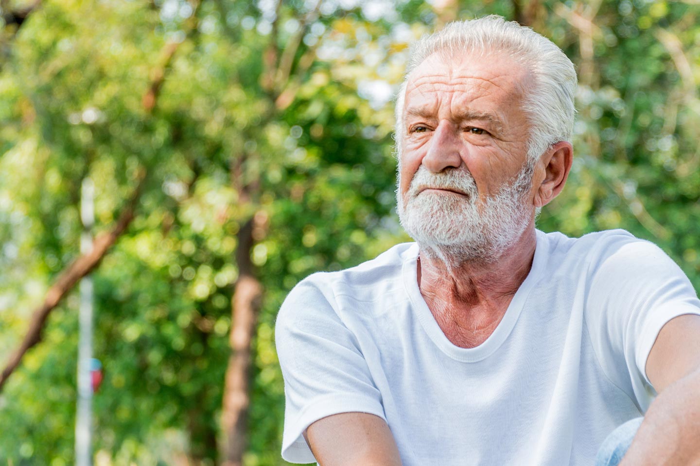 Photo of a man wearing a white t shirt sitting outside