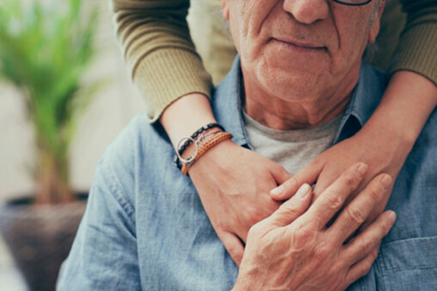 Photo of a senior man embraced by younger arms