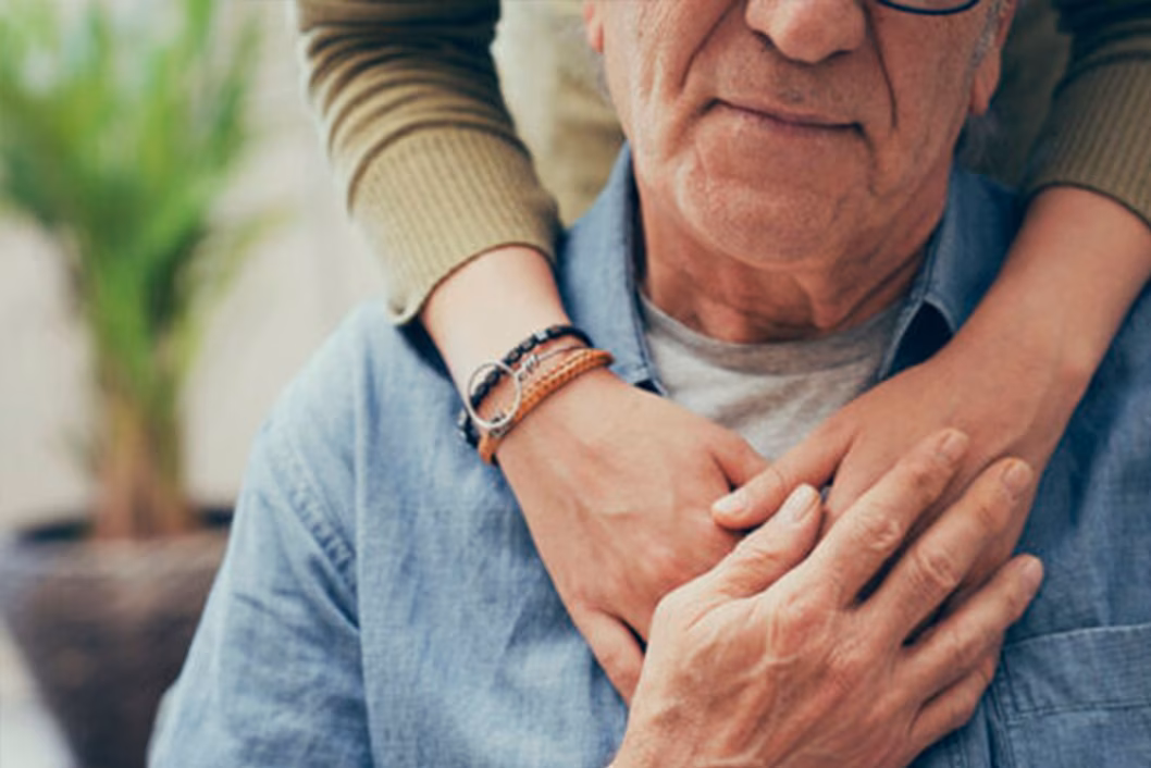 Photo of a senior man embraced by younger arms