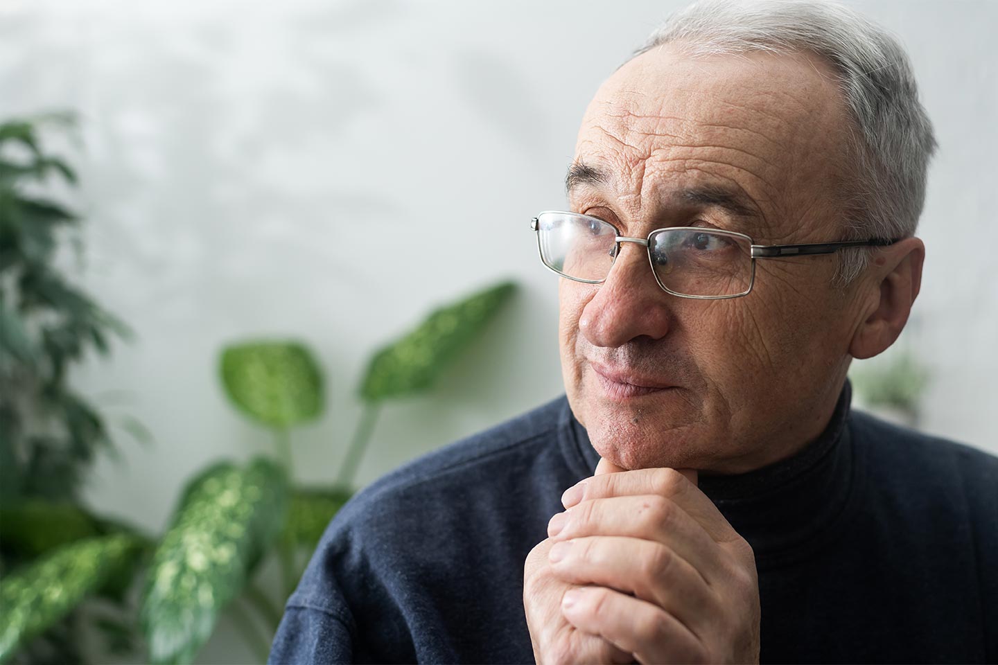Photo of a man sitting in front of some indoor plants