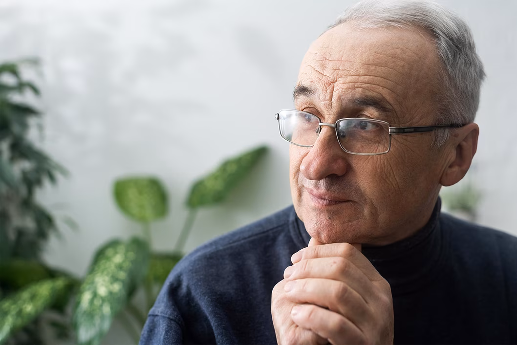 Photo of a man sitting in front of some indoor plants