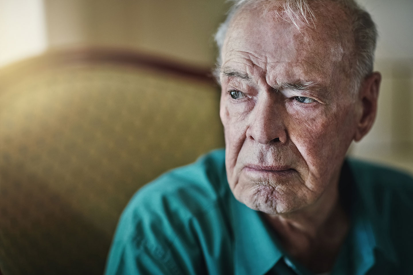 Photo of a man in a green shirt on a gold coloured setee
