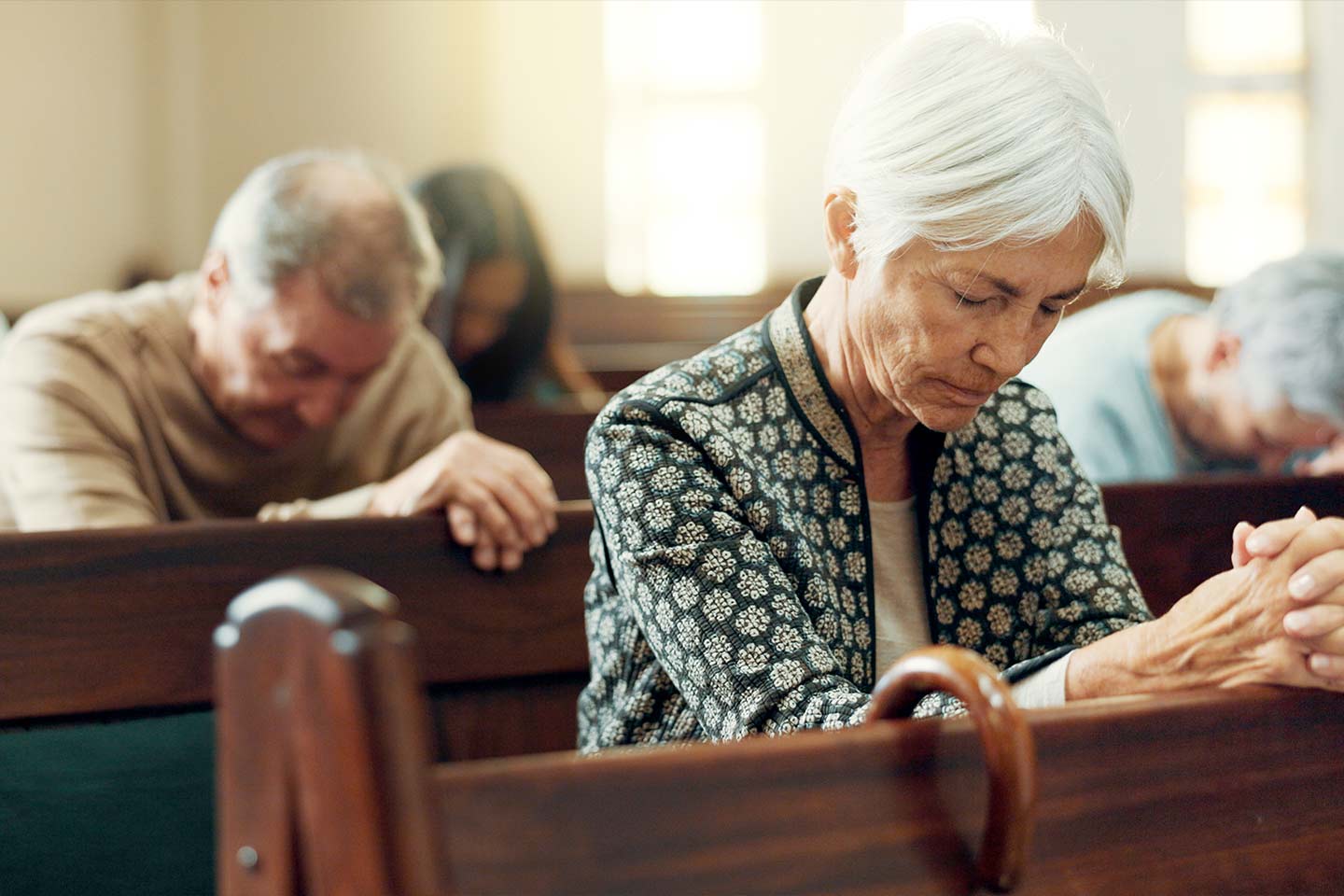 Photo of a woman and three others praying in a church
