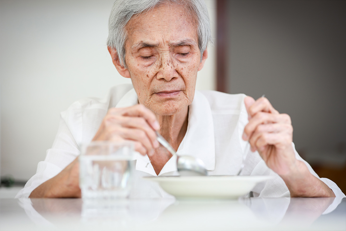 Photo of a person in a white shirt sitting at a dining table